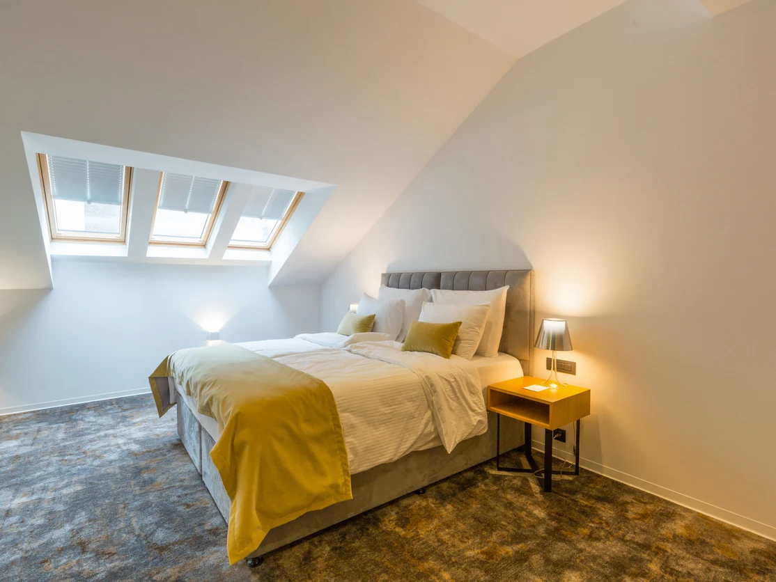 Loft conversion bedroom with sloped white painted ceiling and skylights in Preston by Rose Decor